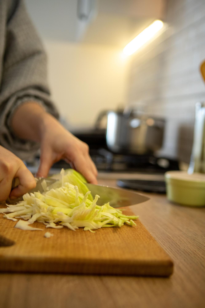 Person schneidet Gemüse in der Küche und bereitet eine frische Mahlzeit zu.