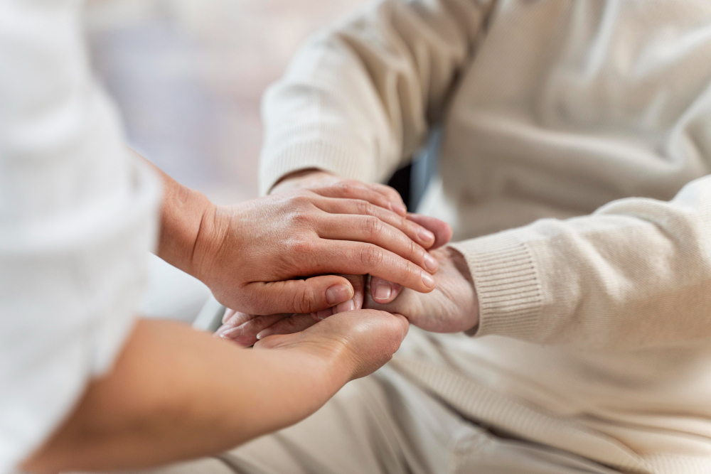 Pflegekraft hält die Hände einer älteren Person und vermittelt Nähe, Sicherheit und persönliche Zuwendung.